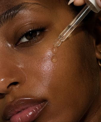 Close-up of a serum dropper beside the cheek